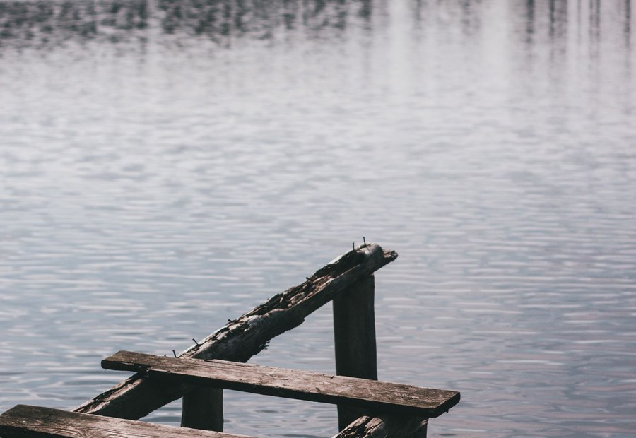 Steel guide pole and driven piling holding a floating dock against a red-clay Lake Norman bank